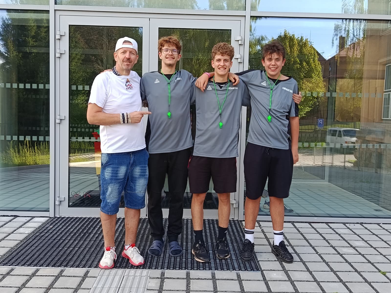 Trenér s novými rozhodčími Apexu — Gabriel Max Pazderník, Nicolas Jack Pazderník a Marek Herbrych s píšťalkami před halou